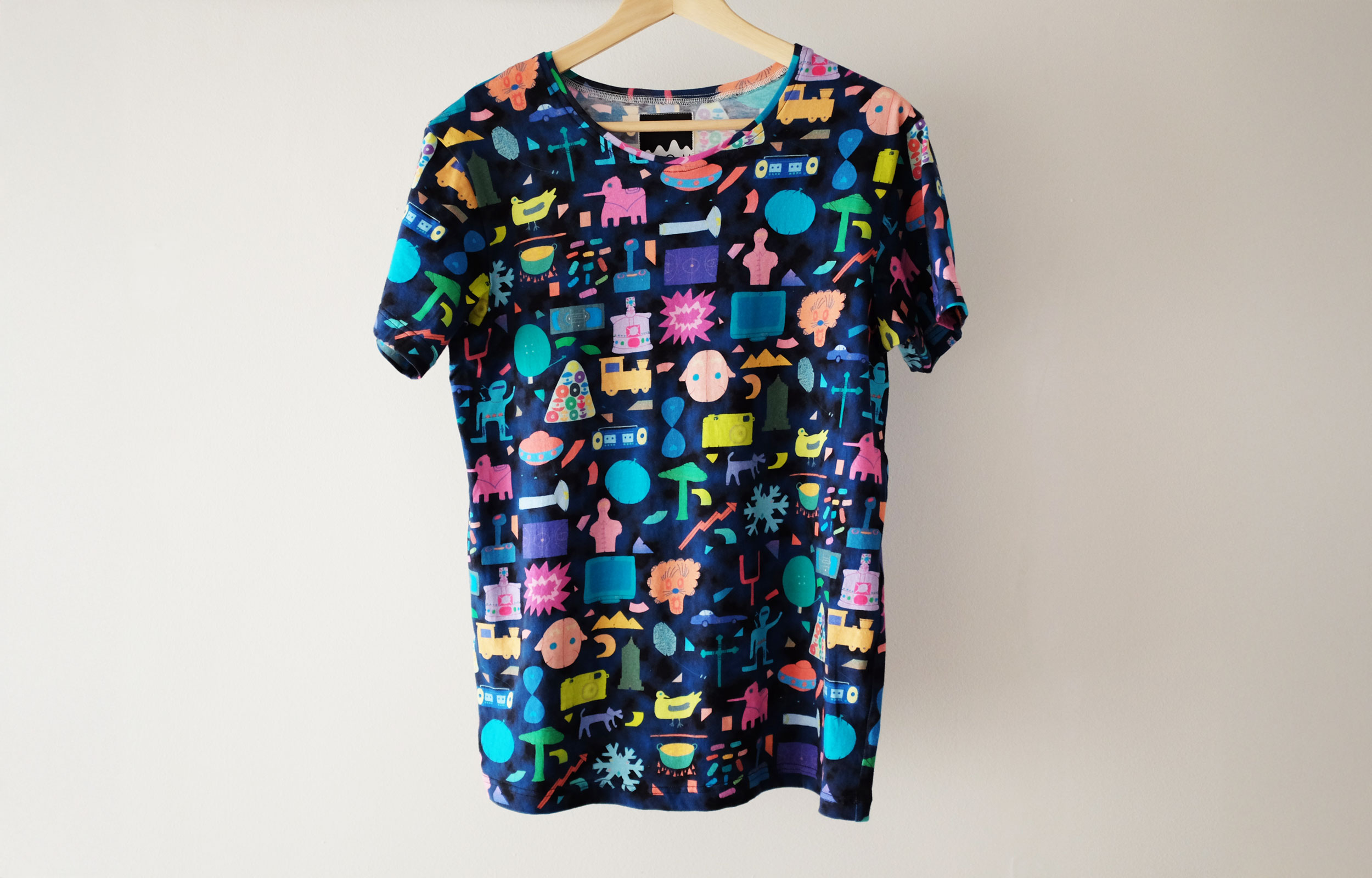 Black T-shirt printed with a colourful collage of small objects