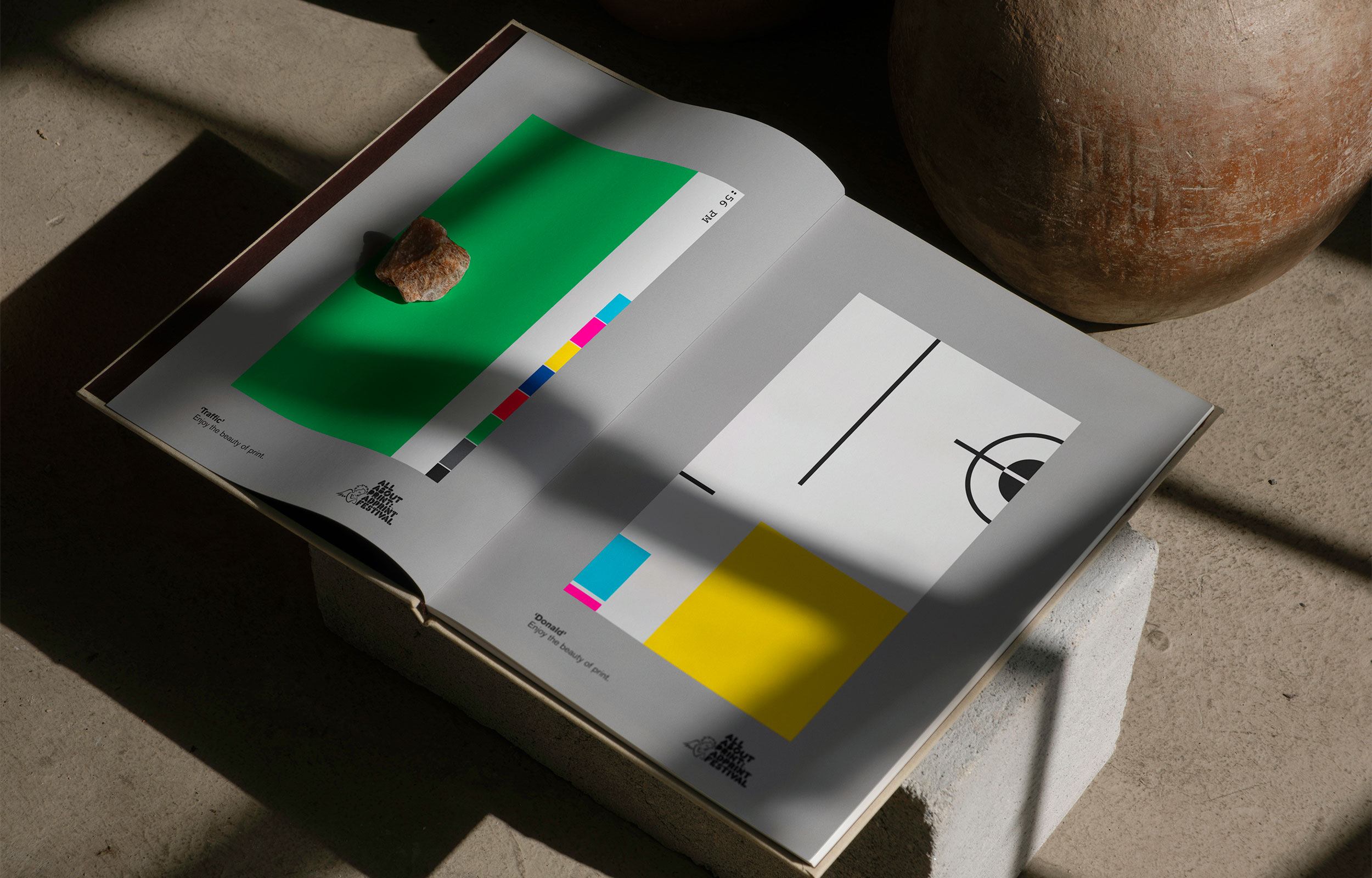 Stack of folded AdPrint posters in a grey, green, yellow, and cyan palette