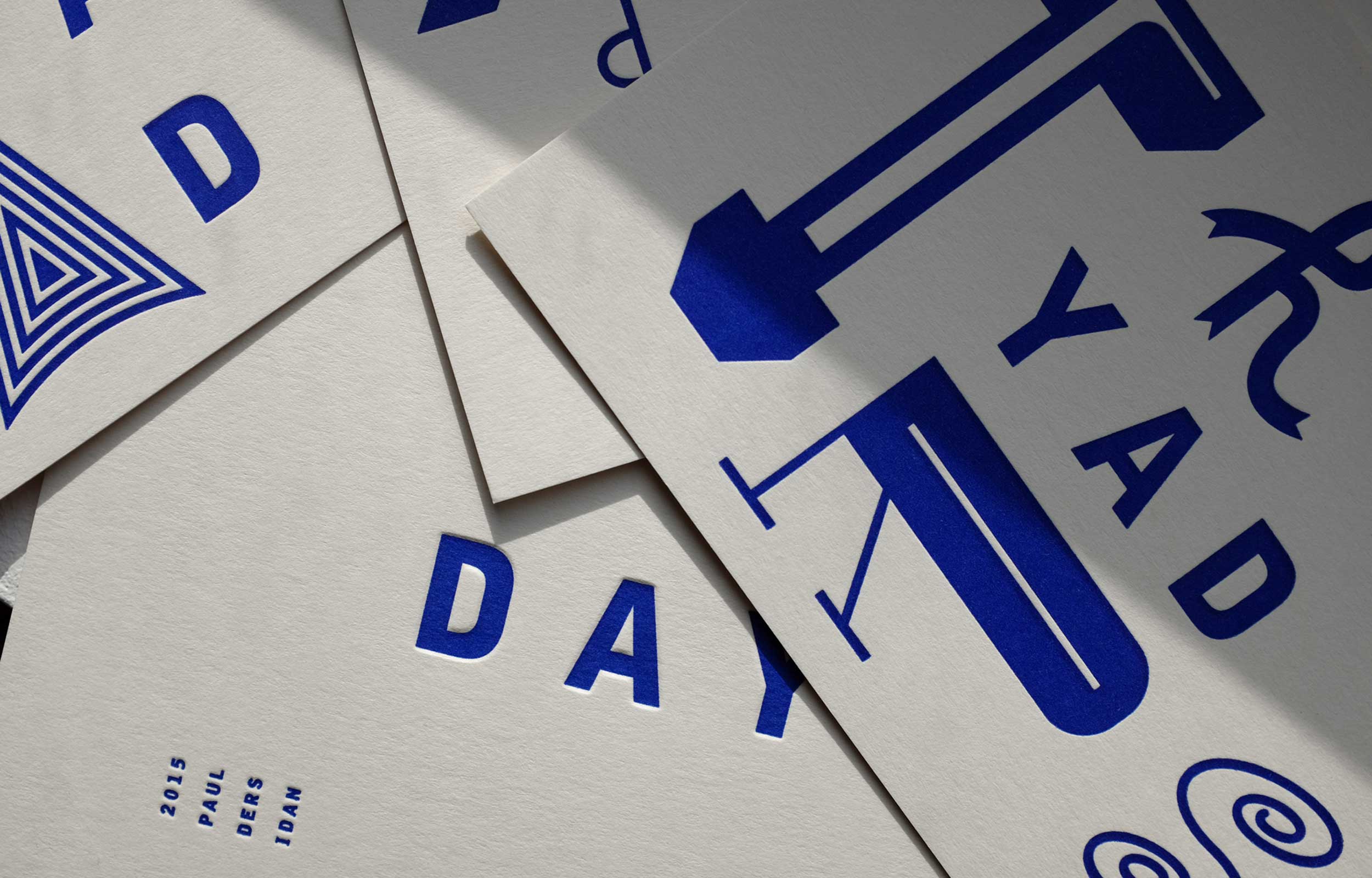 Overlapping printed cards showing blue abstract letterforms