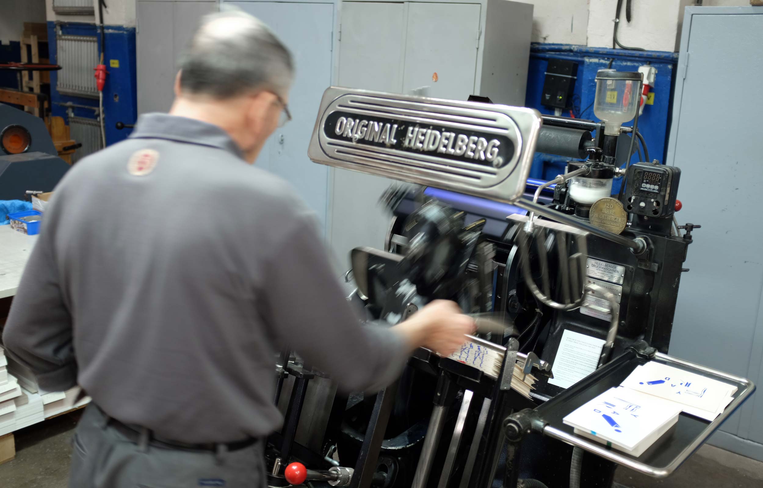 Printer operating a vintage Heidelberg printing press