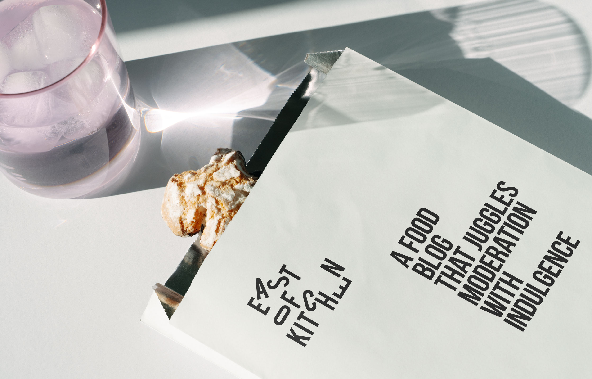 East of Kitchen menu card beside a glass of iced water and a breaded food bite