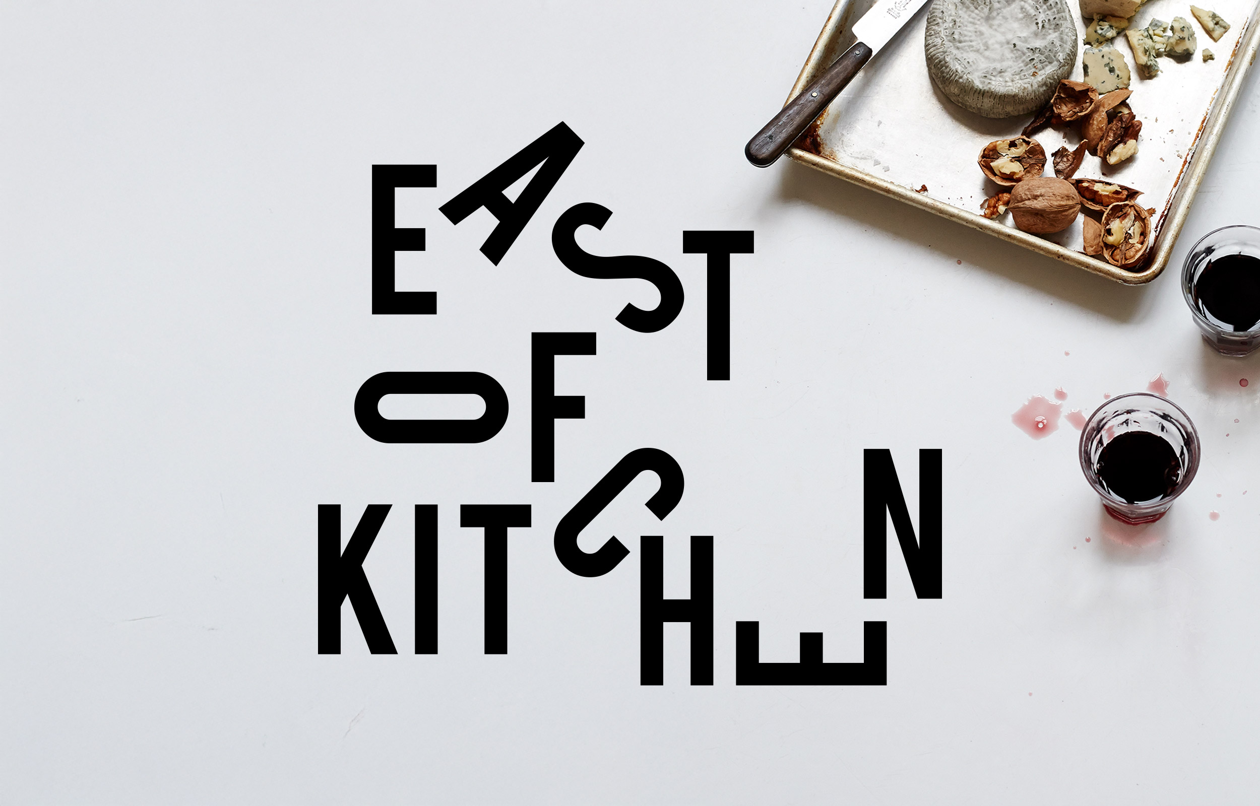 East of Kitchen logo in rearranged black letters on a white tabletop