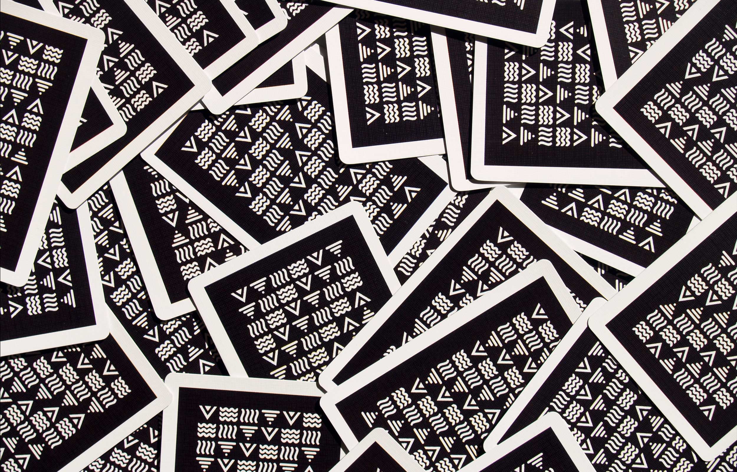 Overlapping black playing-card backs printed with white geometric patterns