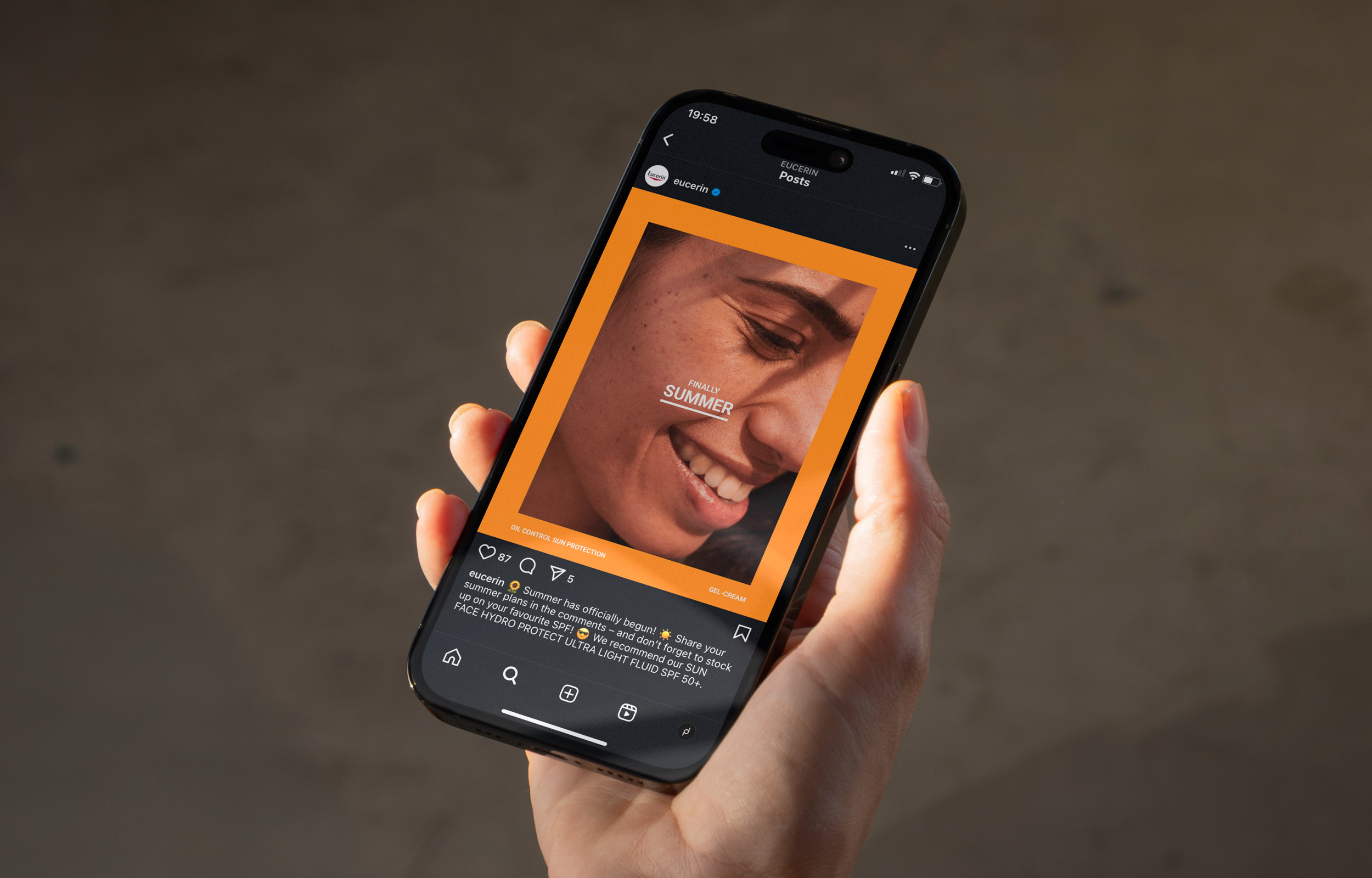 Hand holding a smartphone with a smiling portrait framed in orange