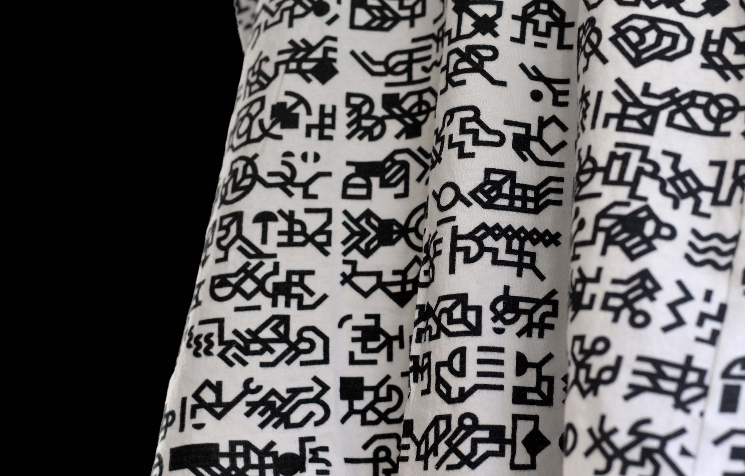 Close-up of black geometric glyphs printed across white T-shirt fabric