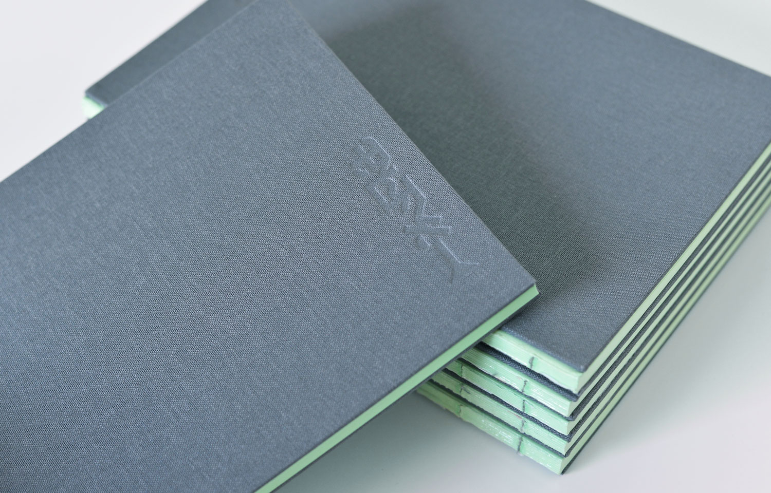 Stack of dark green booklets with pale green page edges
