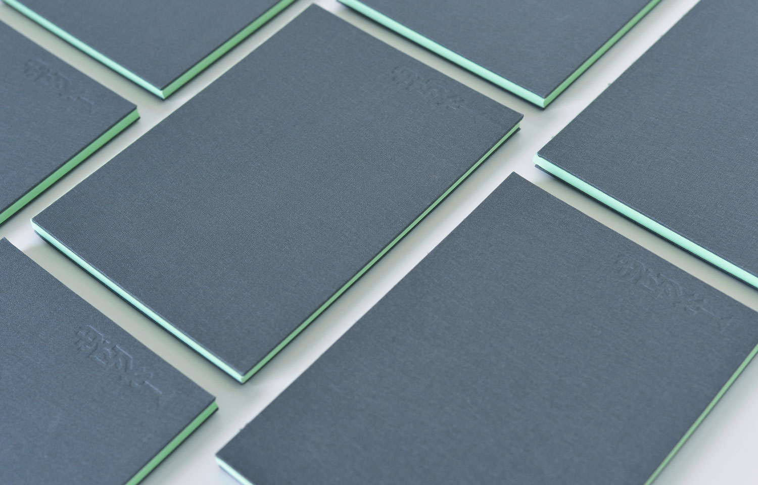 Several dark green booklets arranged in a grid