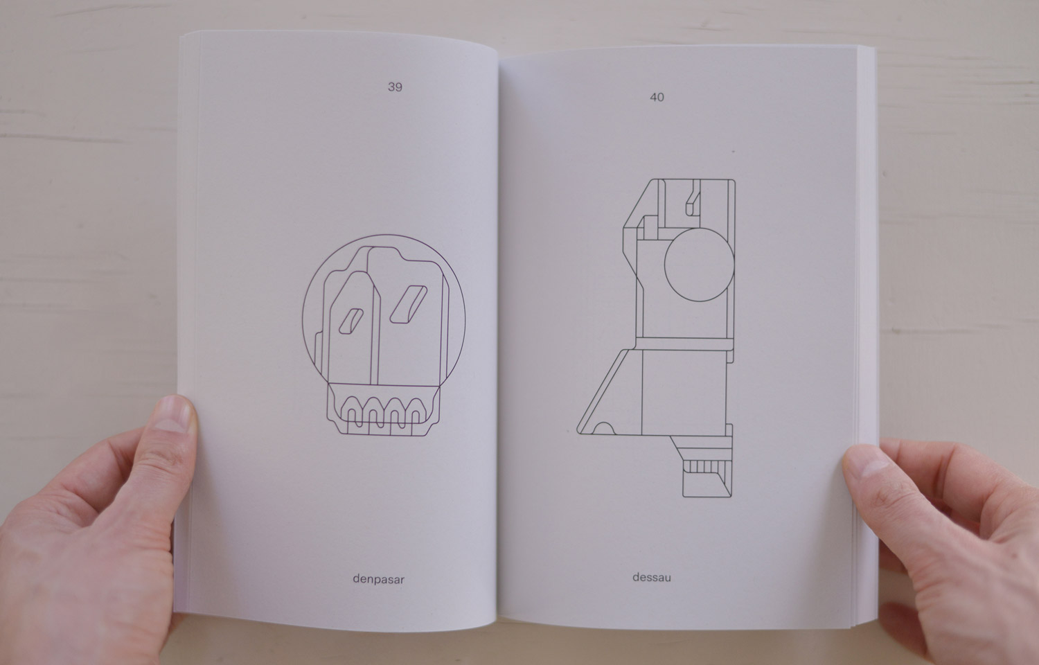 Open book spread with a round line-drawn face and angular geometric figure