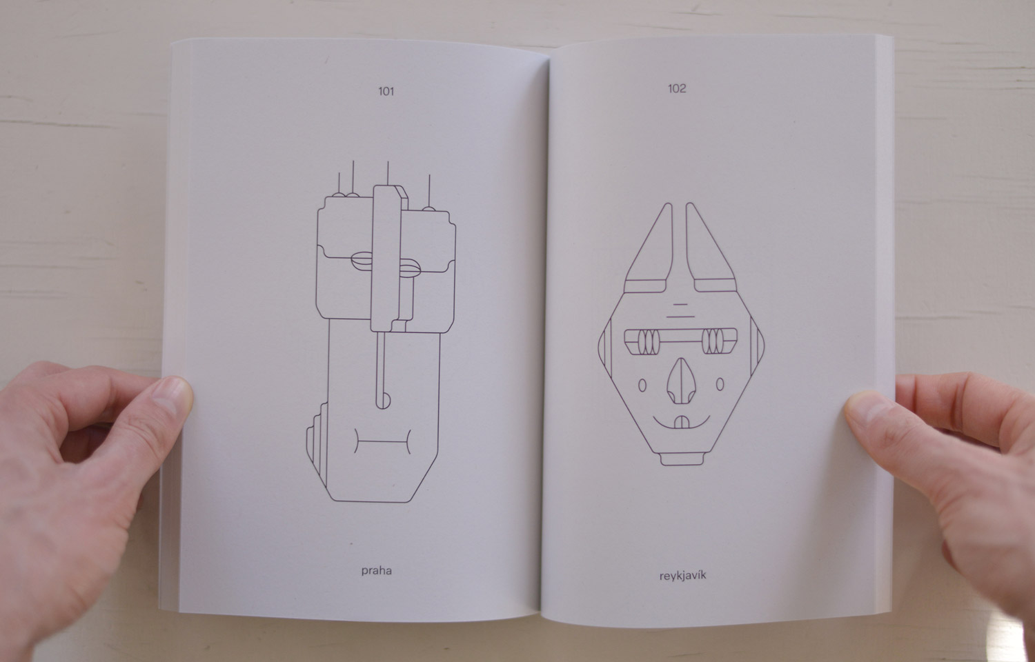 Open book spread with a tall geometric figure and a pointed face drawing