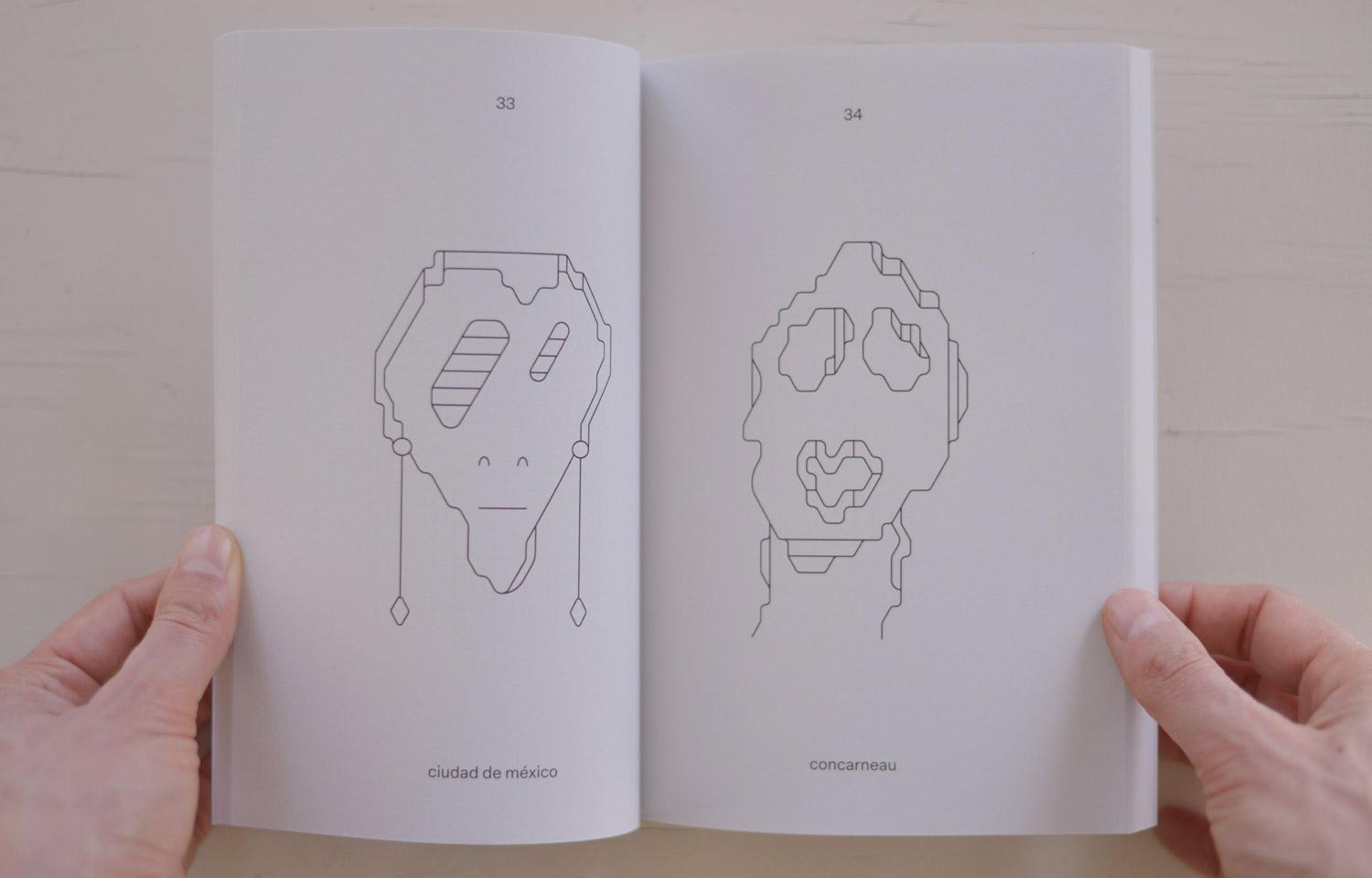 Open book spread with two fine-line abstract face drawings