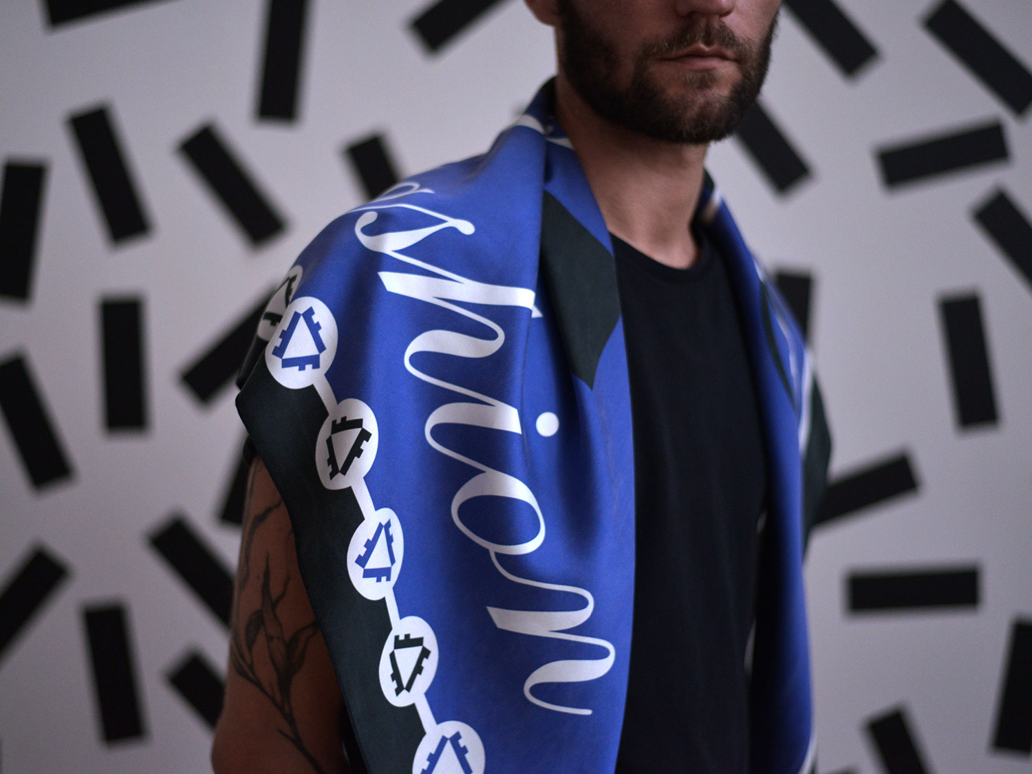 Person wearing the blue patterned scarf draped around their neck