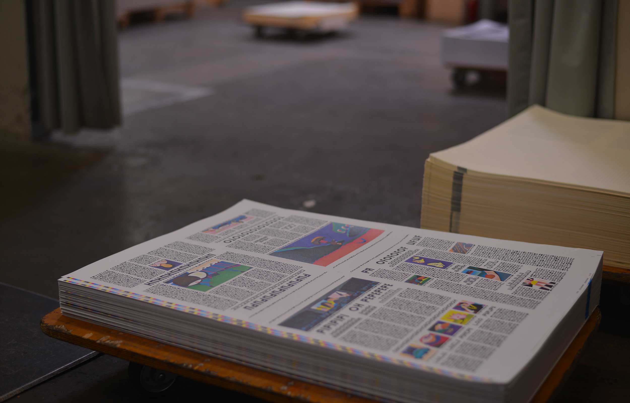 Stack of freshly printed newspaper-style sheets on a printing press