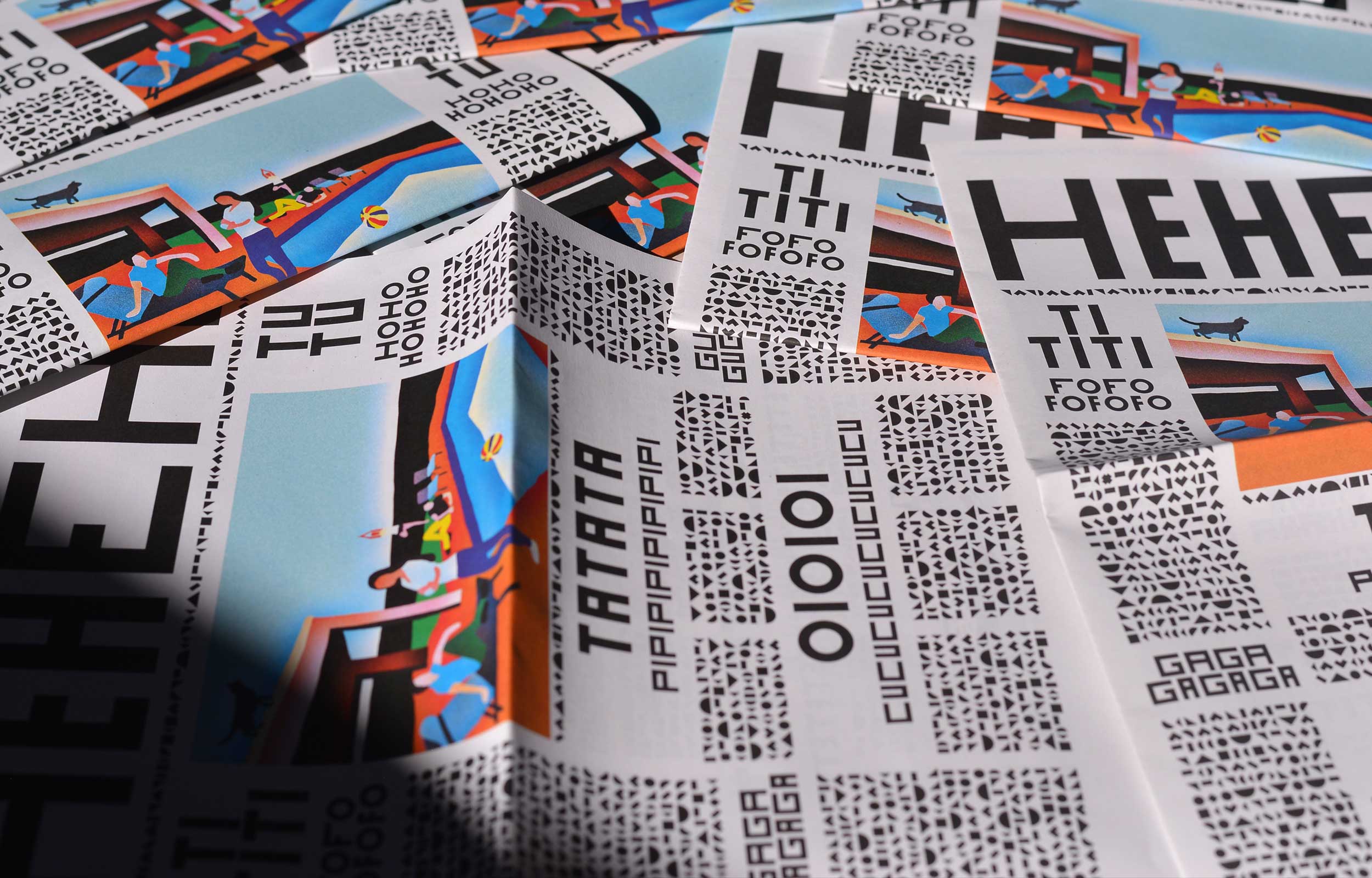 Close-up of stacked newspaper-style prints with black headings and colourful art