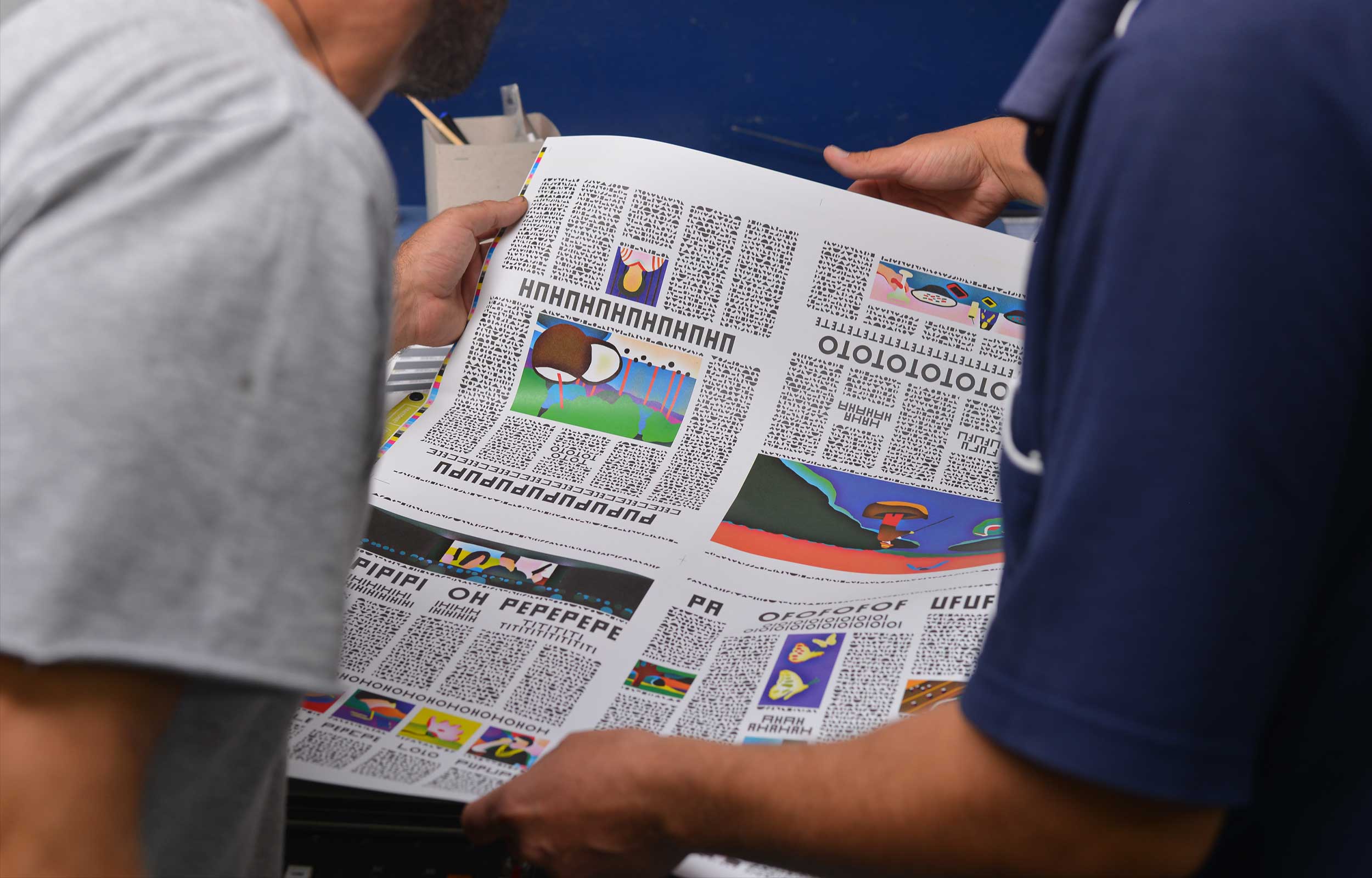 Two people holding and reading a large newspaper-style print