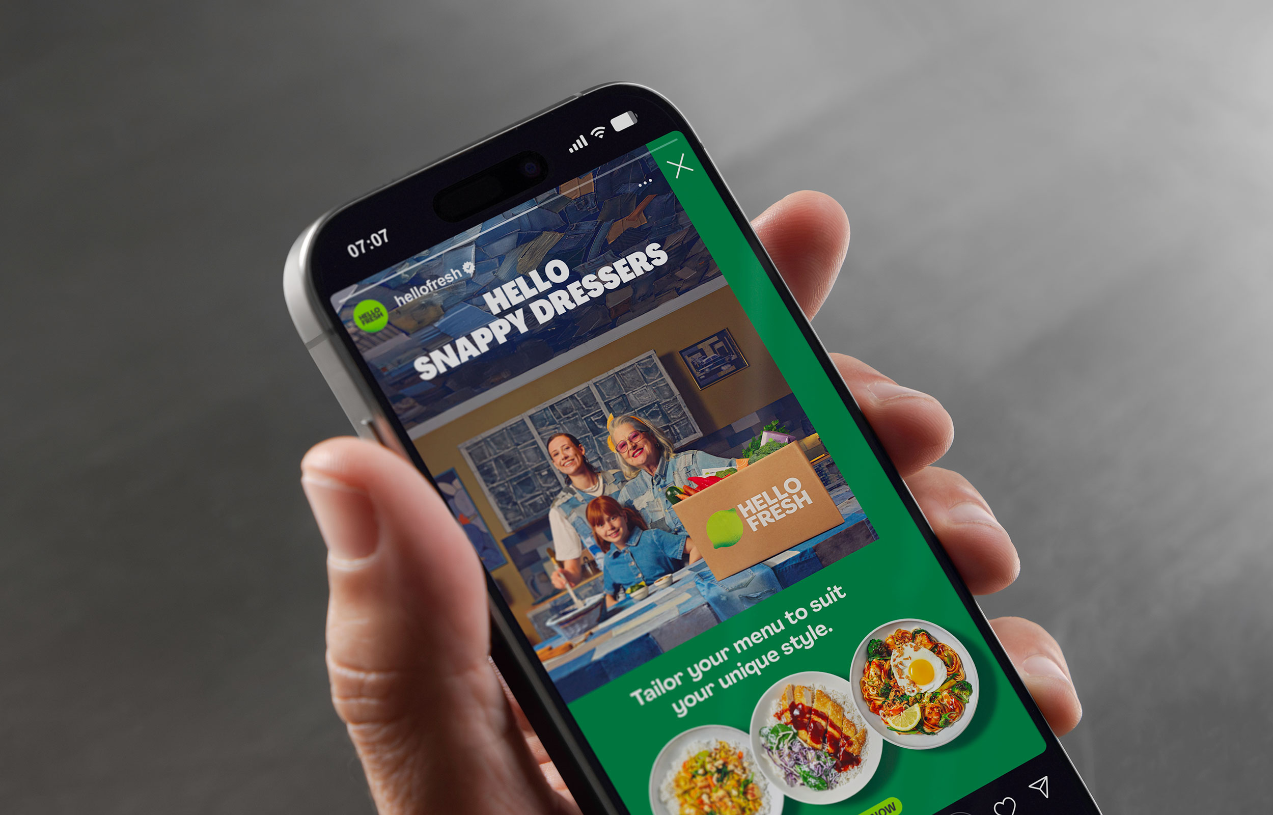 Hand holding a smartphone showing a HelloFresh recipe and meal-selection screen