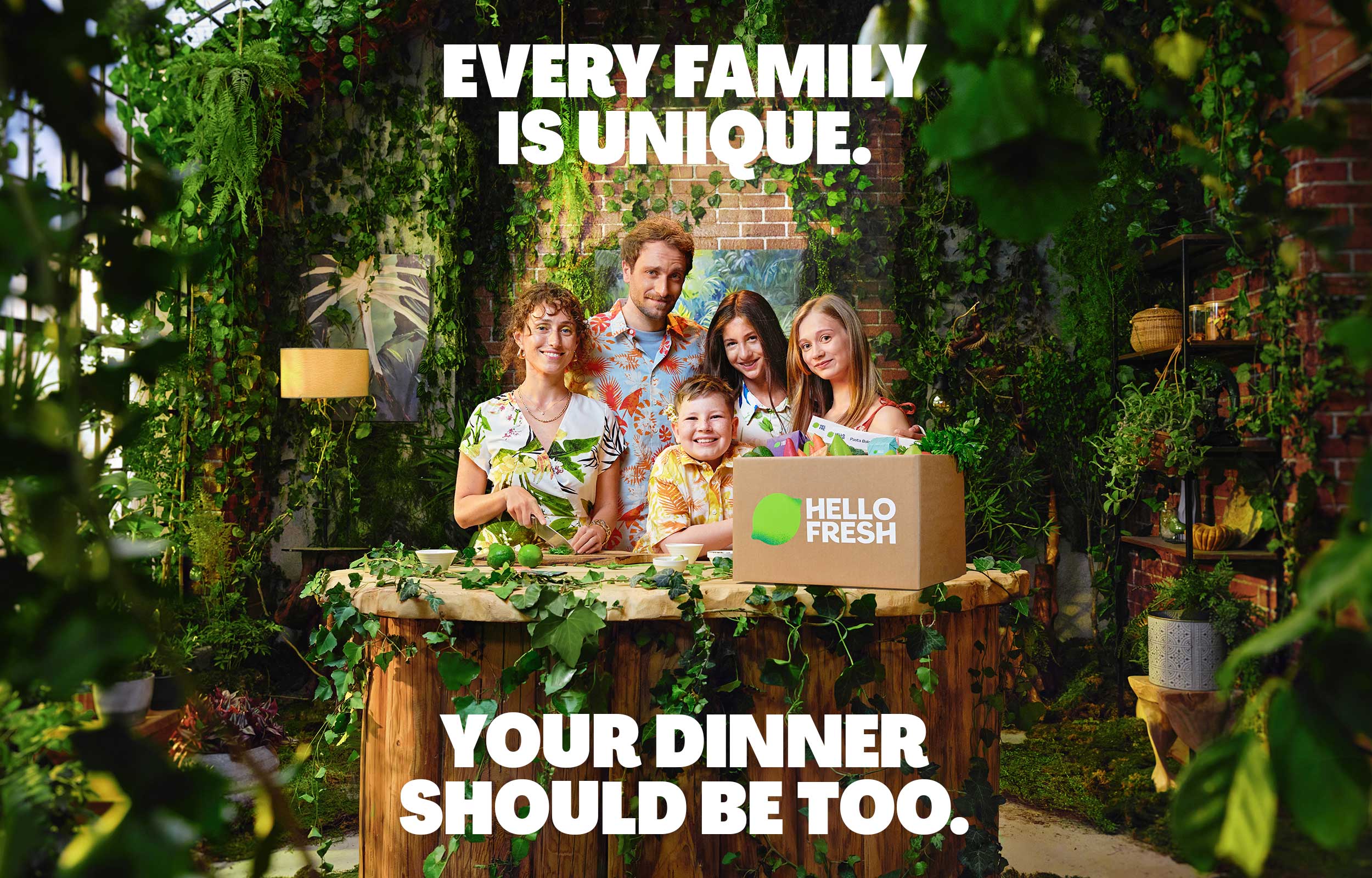 Family holding a HelloFresh box in a lush garden with campaign headline text