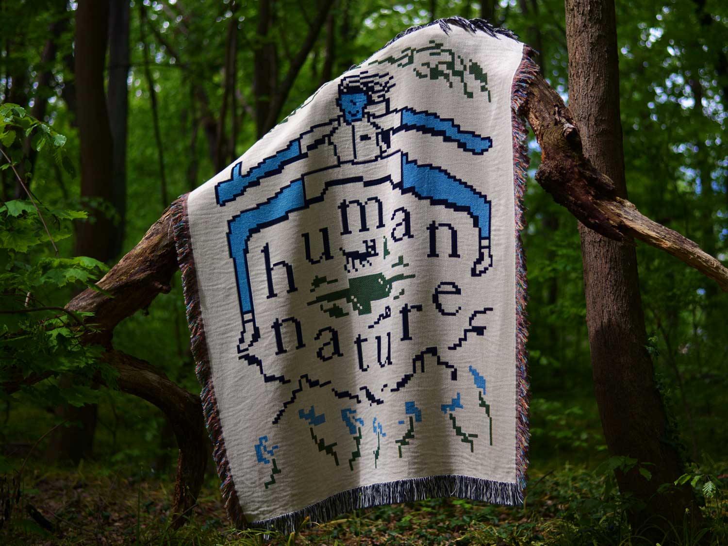 White Human Nature blanket draped over a tree trunk in a forest