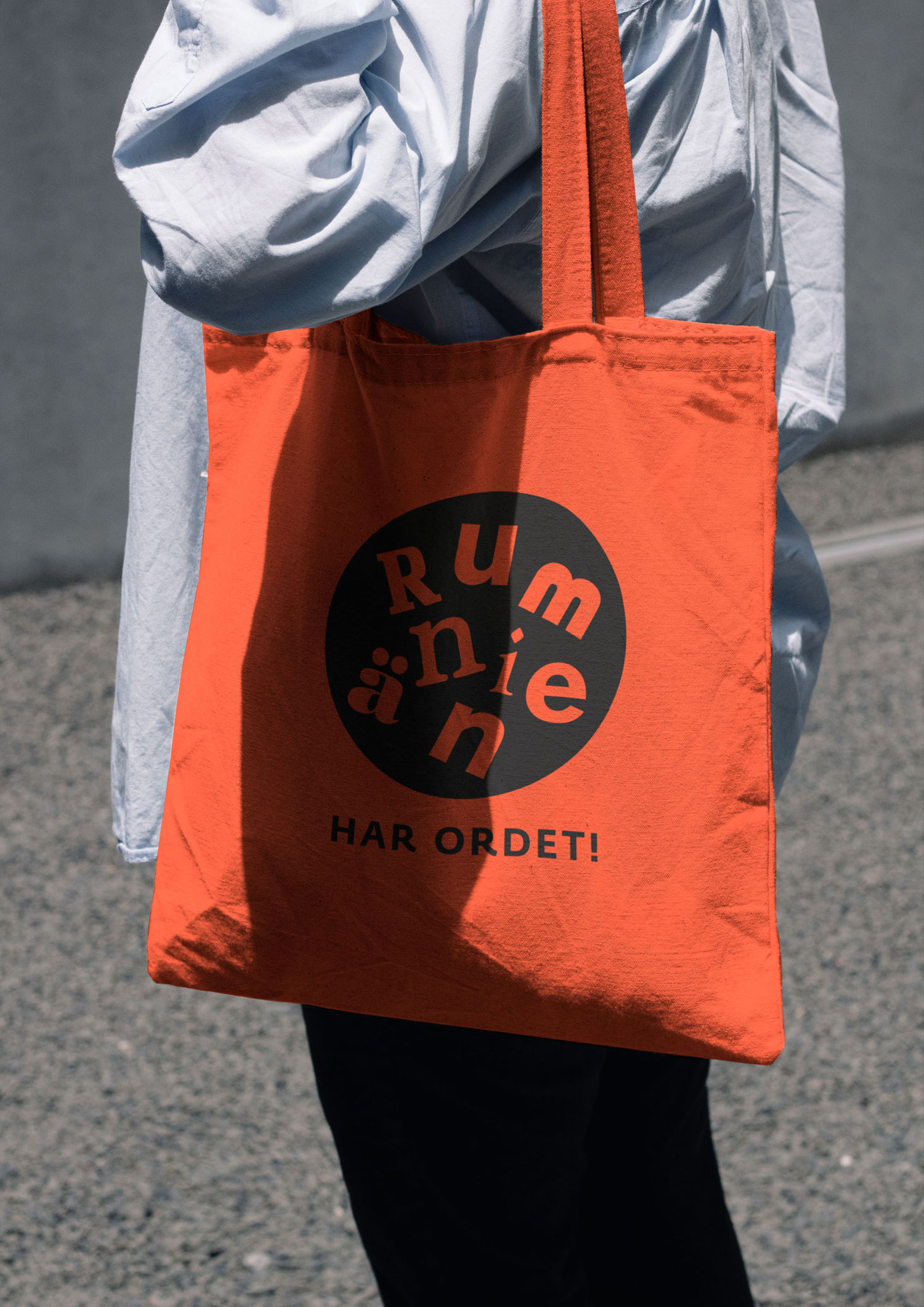 Person carrying an orange tote bag with a black circular Rumänien wordmark