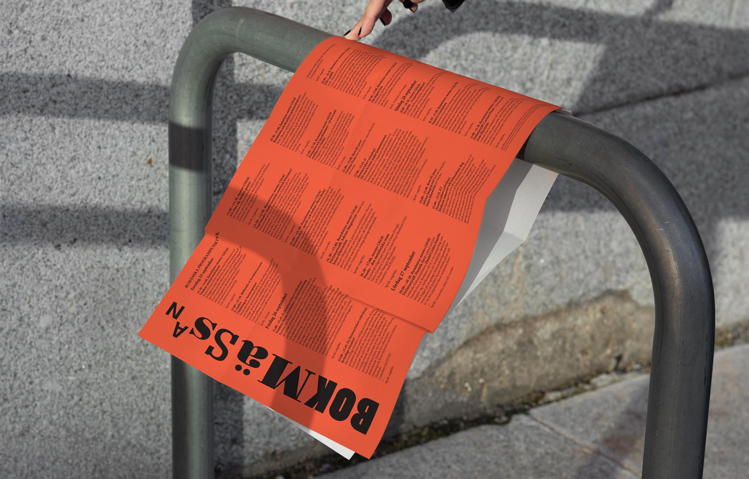 Orange book fair poster draped over a black metal rail outdoors