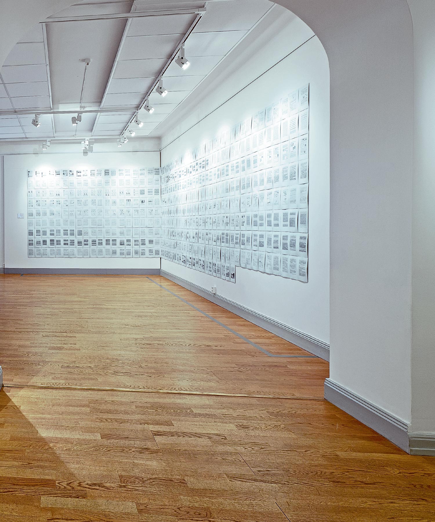 Long white gallery wall covered with a large black-and-white text artwork