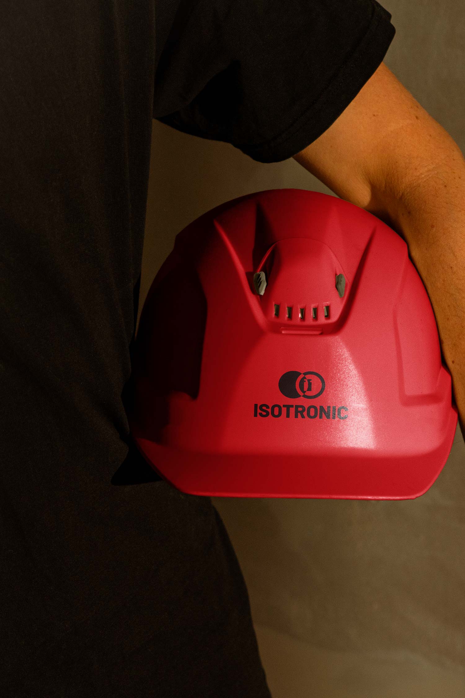Person holding a red Isotronic branded hard hat