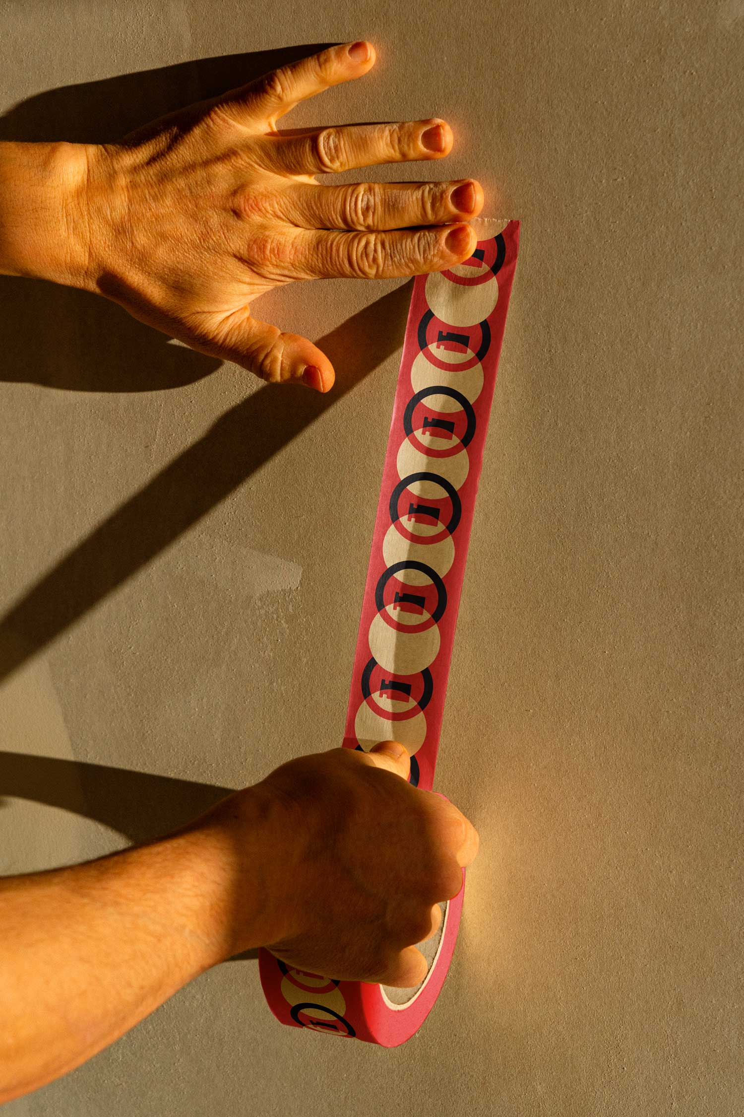 Hands applying a red strip printed with repeating Isotronic circular logos