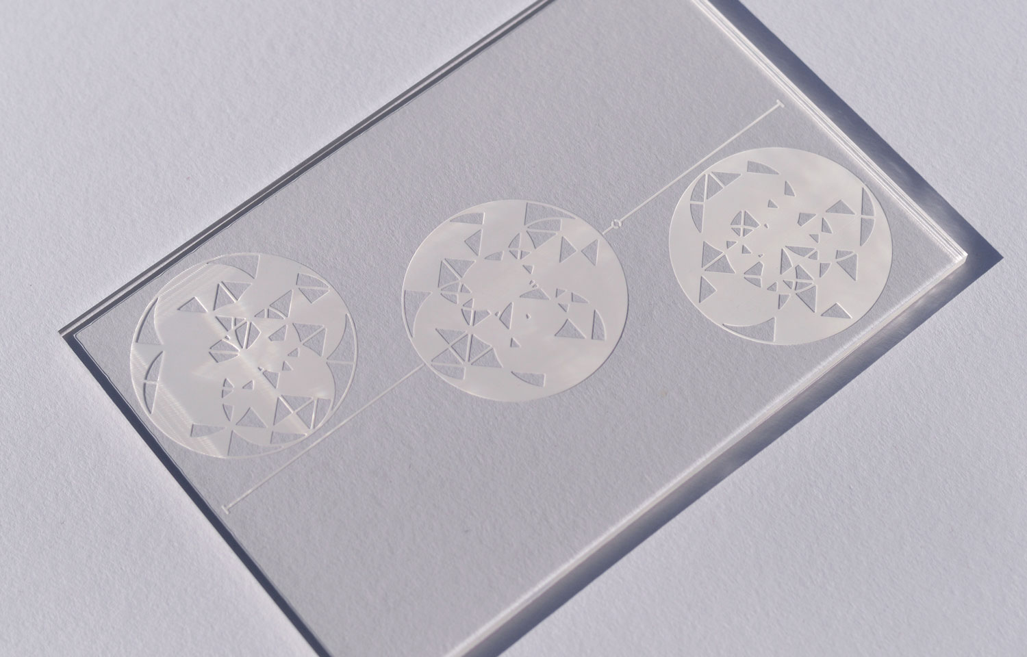 Clear acrylic panel etched with three circular triangular-fragment designs