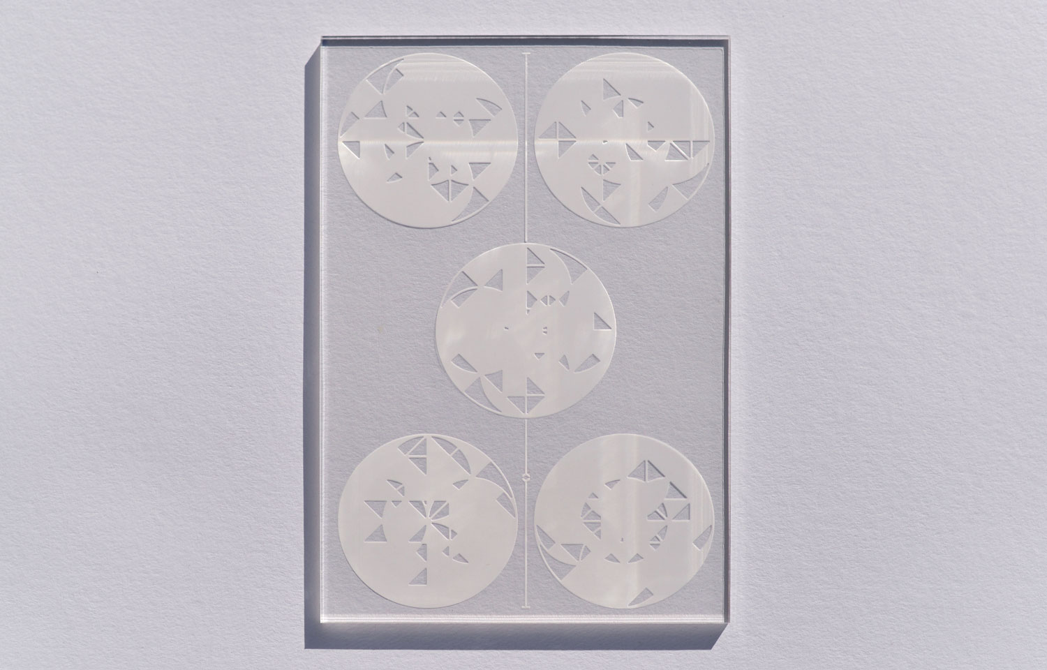 Clear rectangular panel etched with five circular triangular-fragment designs
