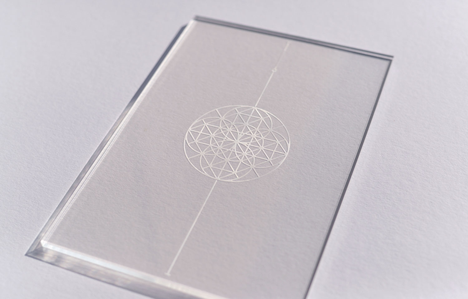 Clear acrylic panel etched with a small geometric circle and vertical line