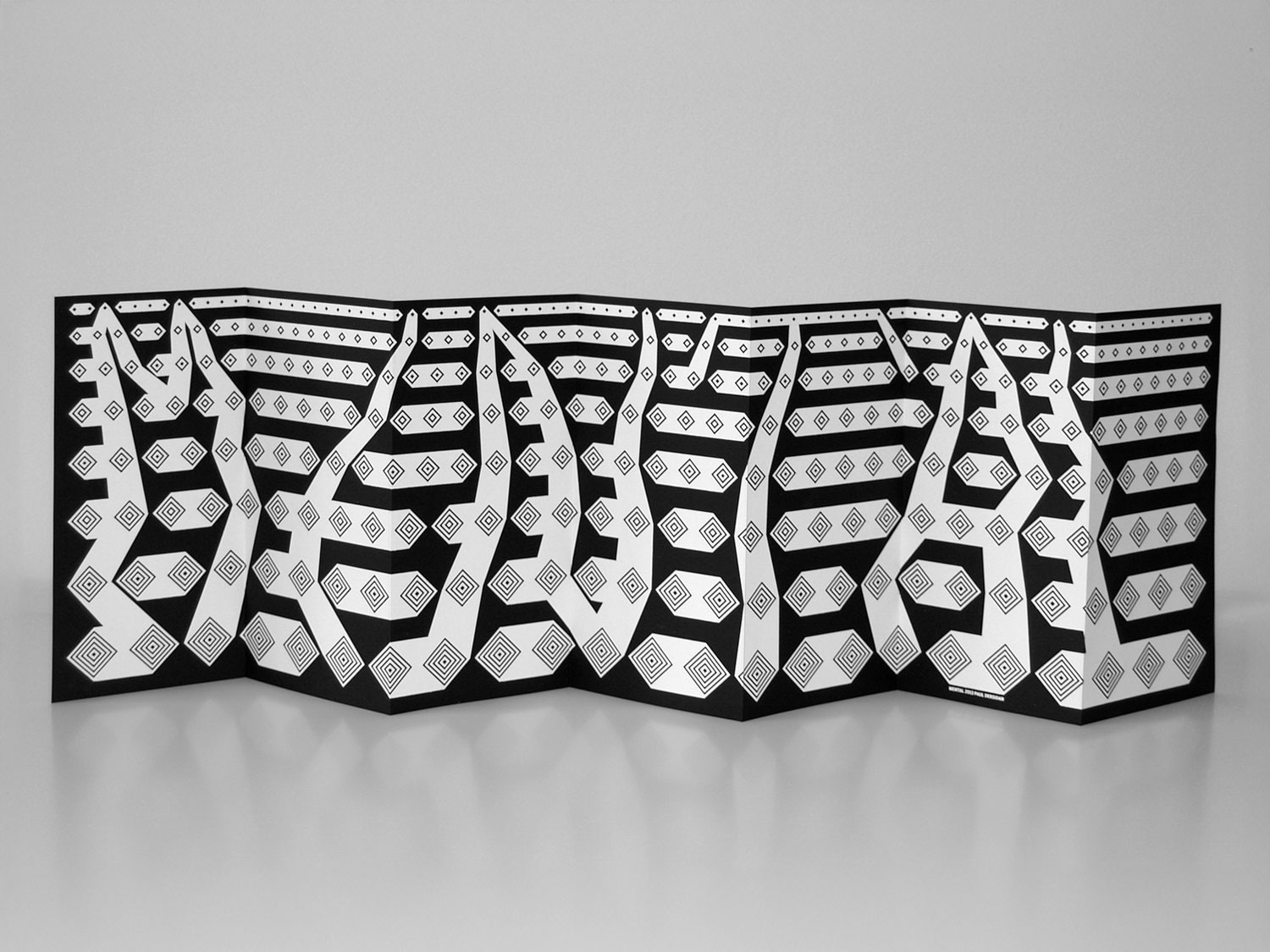 Photograph of a black-and-white geometric banner hanging on a white wall