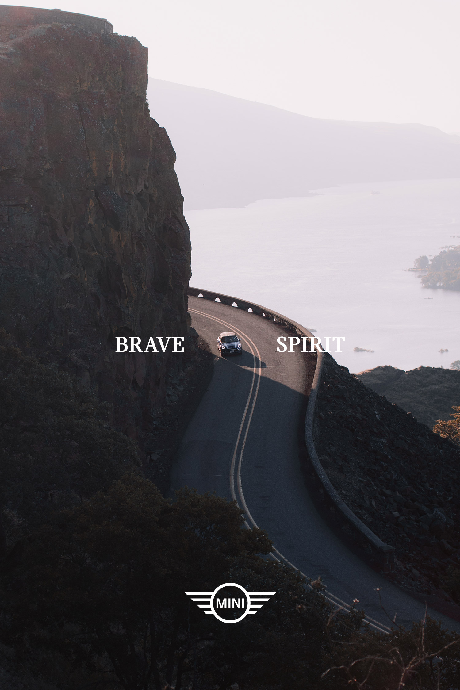 Winding coastal road beside cliffs with Mini badge and small white words