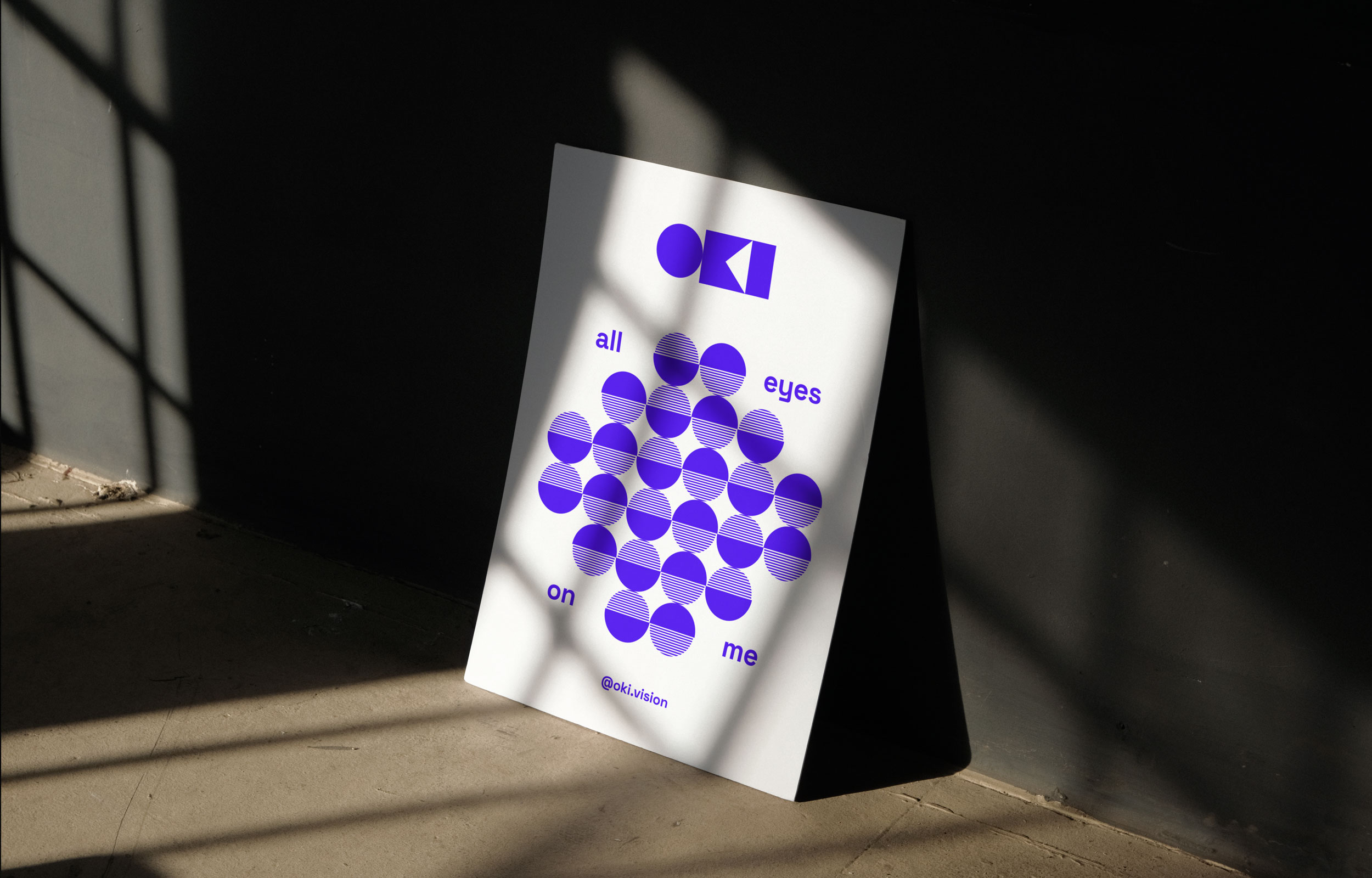 Freestanding white Oki All Eyes on Me poster in angled window light