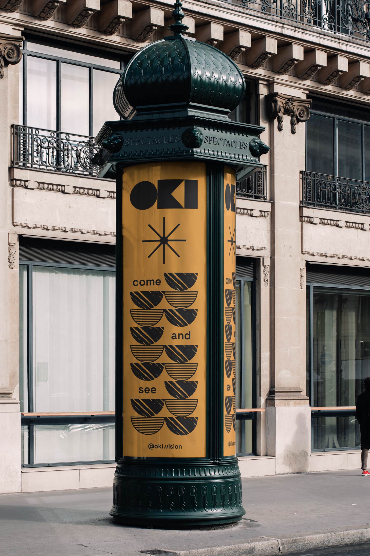 Tall Oki poster with black abstract icons wrapped around a street column