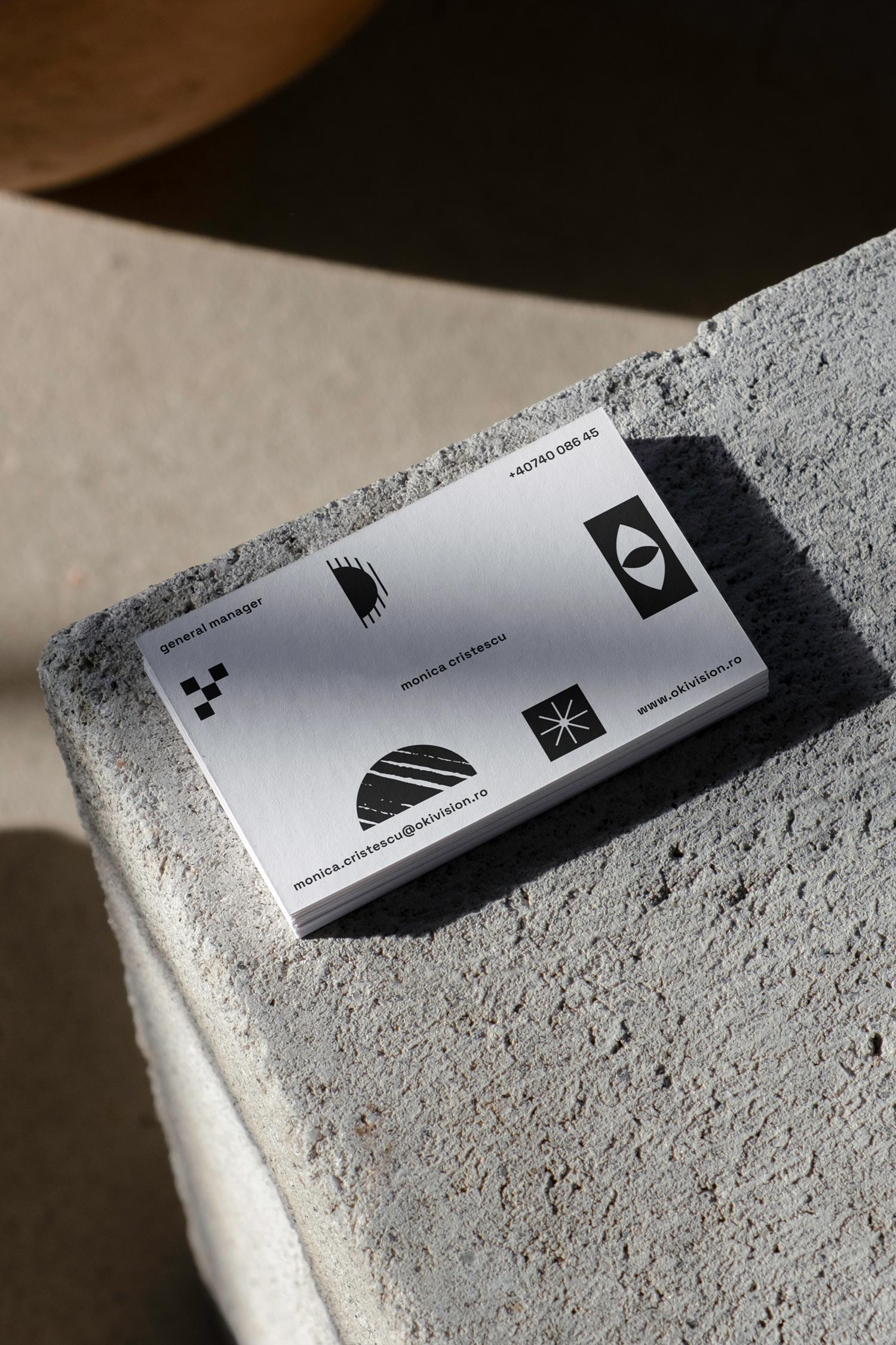 Small white booklet printed with black Oki geometric icons on a concrete block