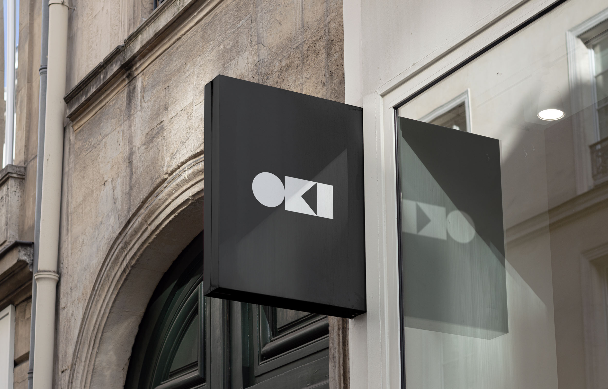 Black exterior Oki hanging sign outside a stone building