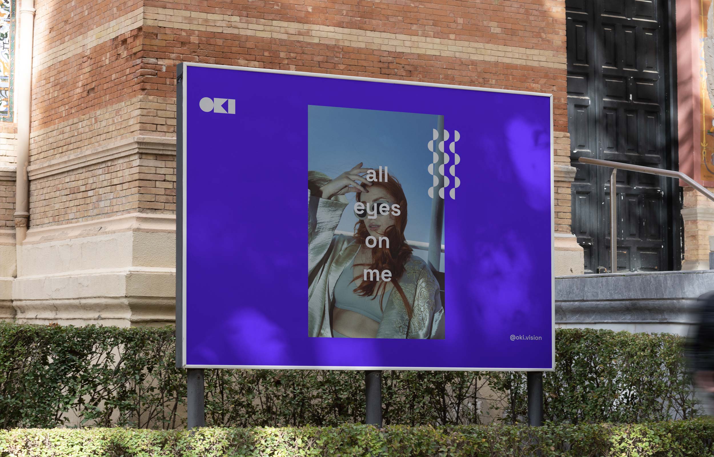 Purple Oki All Eyes on Me billboard mounted outside a brick building