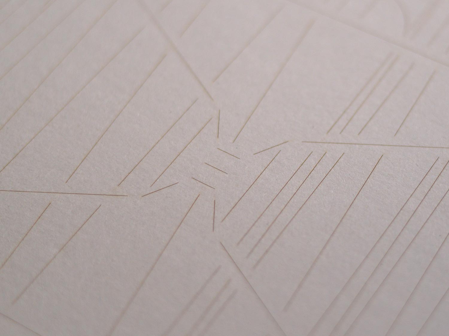 Close-up of pale embossed card with intersecting angular line patterns