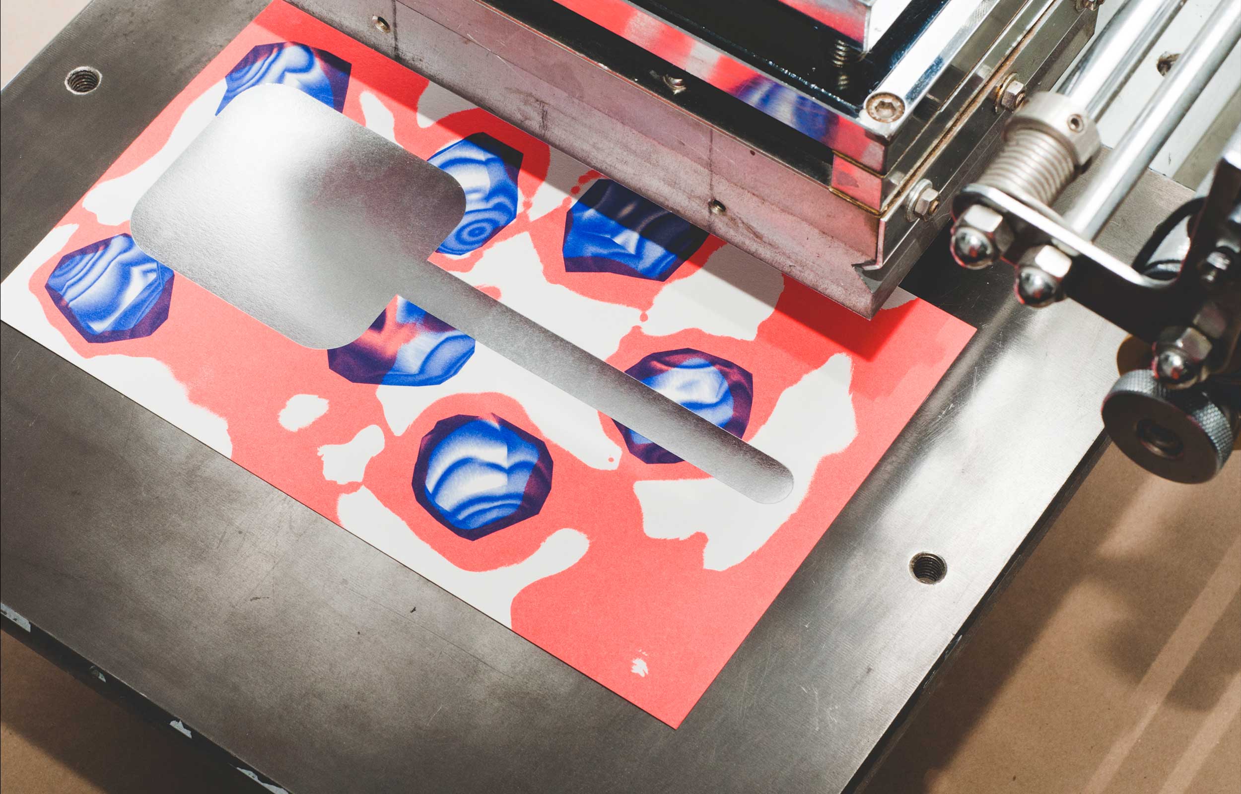 Screen-printing a red, blue and silver graphic on a printing press